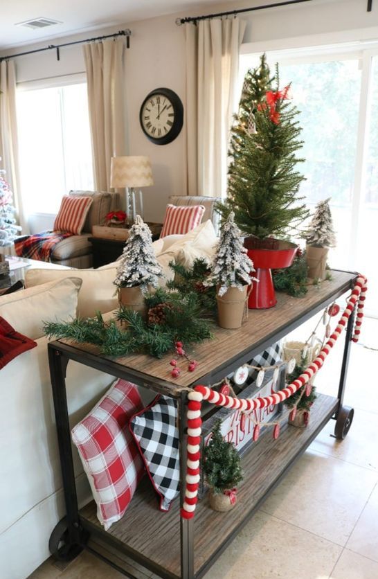 a wooden cart with pompom garlands, plaid pillows. flocked trees in pits and a large tree on a red stand for Christmas