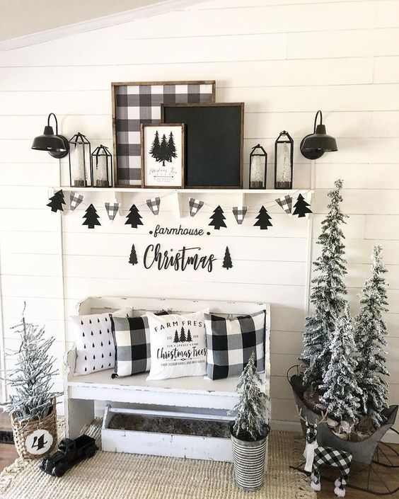 black and white farmhouse entryway with plaid pillows, buntings, artworks and flocked Christmas trees in buckets and baskets