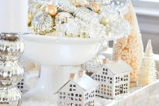 refined vintage Christmas decor with a tray, little houses, bottle brush trees, pillar candles and a bow with mercury glass ornaments
