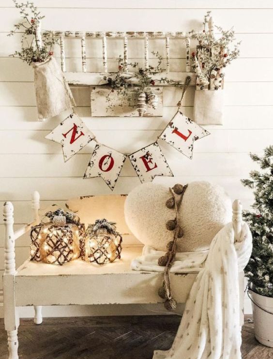 white vintage Christmas decor with a shabby chic rack and a bench, white pillows, candle lanterns and a Christmas bunting plus snowy branches
