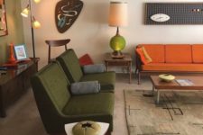 a boho mid-century modern living room with green, rust, neutral items, lamps and quirky artworks