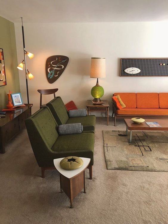 A boho mid century modern living room with green, rust, neutral items, lamps and quirky artworks