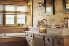 a cabin bathroom clad with wood, with a bathtub clad with wood, a double vanity of wood and two mirrors is welcoming