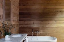 a chalet bathroom clad with wood, with an oval tub, a wooden vanity with a double sink is very simple and very inviting