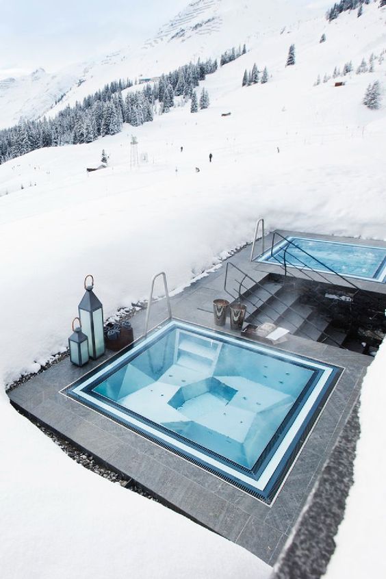 A double built in jacuzzi with tile decks around placed right into the snow, with a mountain and forest view is amazing