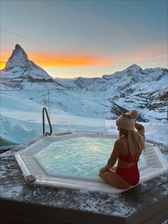 a hexagon jacuzzi with a stone deck and a jaw-dropping snowy mountain view is a perfect addition to a chalet