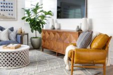 a mid-century modern living room with mustard and blue furniture, an inlay sideboard and a rug with boho embroidery