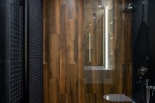 a minimalist bathroom clad with small black tiles and with wood-like tiles for a super elegant and contrasting look