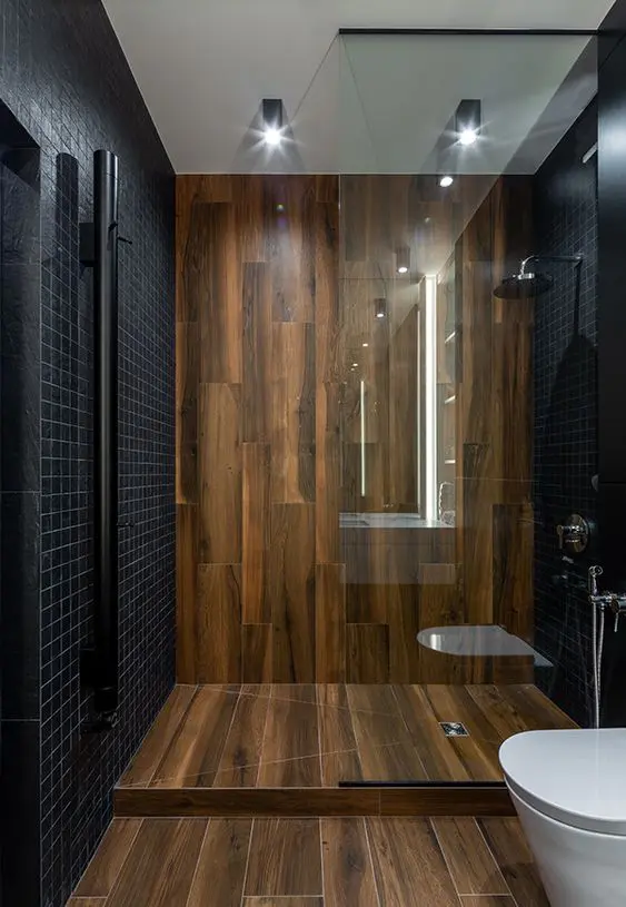 A minimalist bathroom clad with small black tiles and with wood like tiles for a super elegant and contrasting look