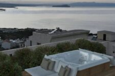 a rooftop jacuzzi with a step deck and pillows and a gorgeous sea view is a fantastic space to be in