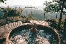 a round built-in jacuzzi with a wooden deck around and a dream catcher over it, with a lovely forest view is a fantastic idea for everyone