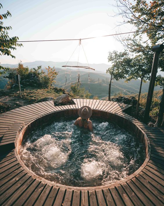 A round built in jacuzzi with a wooden deck around and a dream catcher over it, with a lovely forest view is a fantastic idea for everyone
