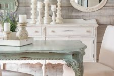 a shabby chic meets rustic dining room with rough wooden walls, a gallery wall with mirrors and art, a mint-colored table and candles