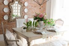 a sweet shabby chic dining room with wooden furniture, pink tulips, a vintage chandelier and a gallery wall with a mirror and plates