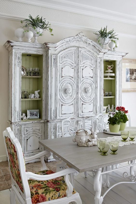 a unique shabby chic dining room with a white buffet, vintage furniture, floral textiles and bold blooms