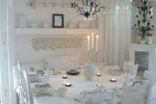 a white shabby chic dining room with lace linens, mismatched chairs, a crystal chandelier and open shelving