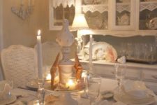 an elegant coastal meets shabby chic dining room with white furniture, a crystal chandelier, candles, starfish, seashells and lace
