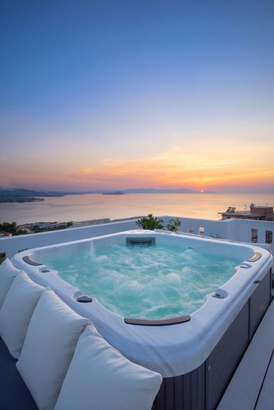 an outdoor jacuzzi with a bench around it and some pillows plus a gorgeous sea view is a fantastic idea for relaxation
