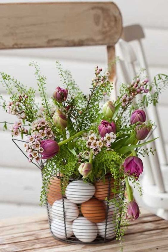 a basket filled with eggs and with greenery and pink blooms on top is a cozy Easter centerpiece