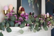 a beautiful spring mantel with lush greenery, blooms and colorful faux eggs in metallic cups for a beautiful look