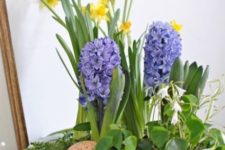 a blue bath with greenery, speckled eggs, yellow daffodils and purple hyacinths for Easter