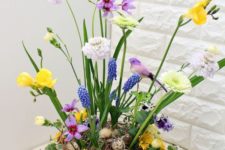a bold Easter flower arrangement with a nest with speckled eggs, bright blooms and fake birds