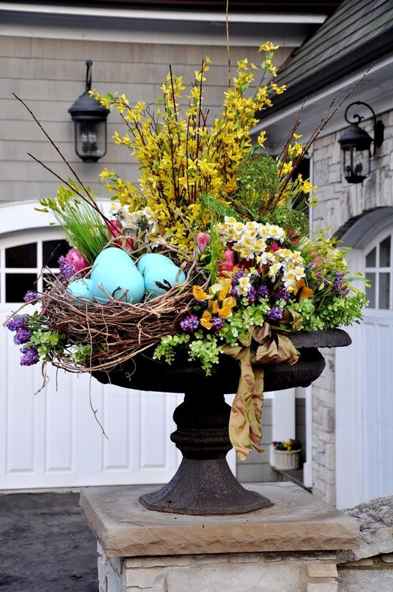 a bright outdoor Easter arrangement with yellow, purple, pink blooms, greenery and large fake blue eggs