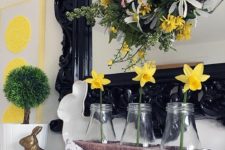 a bright spring mantel with an Easter bunting, some daffodils in bottles, bunnies and a green topiary