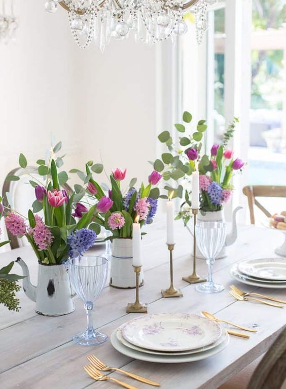 a bright spring table setting with colorful floral centerpieces, gilded touches and an uncovered table