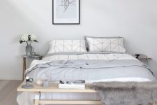a casual Nordic bedroom in off-whites, with a wooden bench, a comfy bed and a pendant lamp for a modern look
