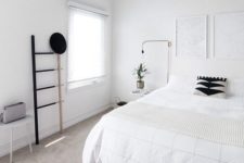 a clean Nordic bedroom with a white bed, artworks, a ladder, lamps and a stool – blakc for drama