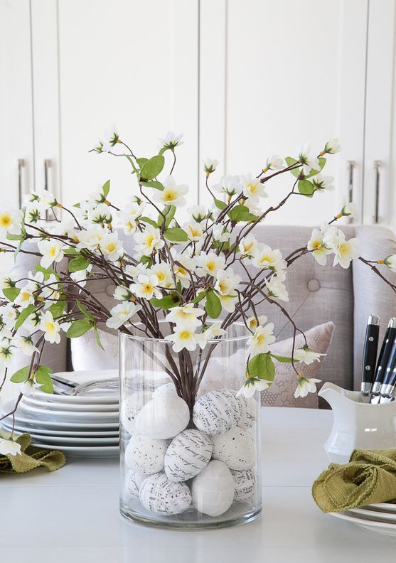 a clear vase with decorated Easter eggs and lush blooming branches is a cool and simple Easter centerpiece