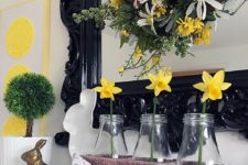 a colorful Easter mantel with bright daffodils and a wreath with blooms and greenery, bunnies and a bunting