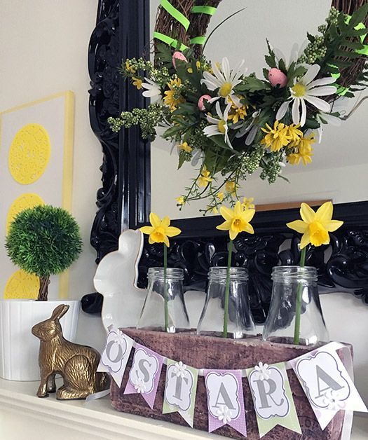 a colorful Easter mantel with bright daffodils and a wreath with blooms and greenery, bunnies and a bunting