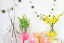 a colorful spring display with moss eggs, bright neon ombre vases and blooming branches and greenery