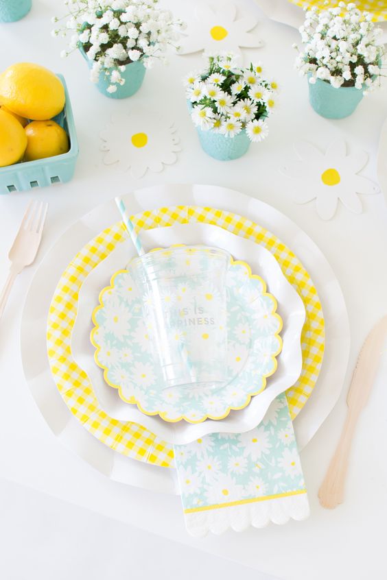a colorful spring table setting with dairy and baby's breath centerpieces, yellow and white porcelain and touches of turquoise