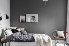 a contemporayr Scandinavian bedroom with a dark wall, monochromatic bedding, lamps and lights and a grey rug