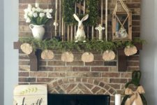 a cozy spring-inspired mantel with fresh greenery, a bunny ass garland, a bunny figurine and some white tulips in a jug