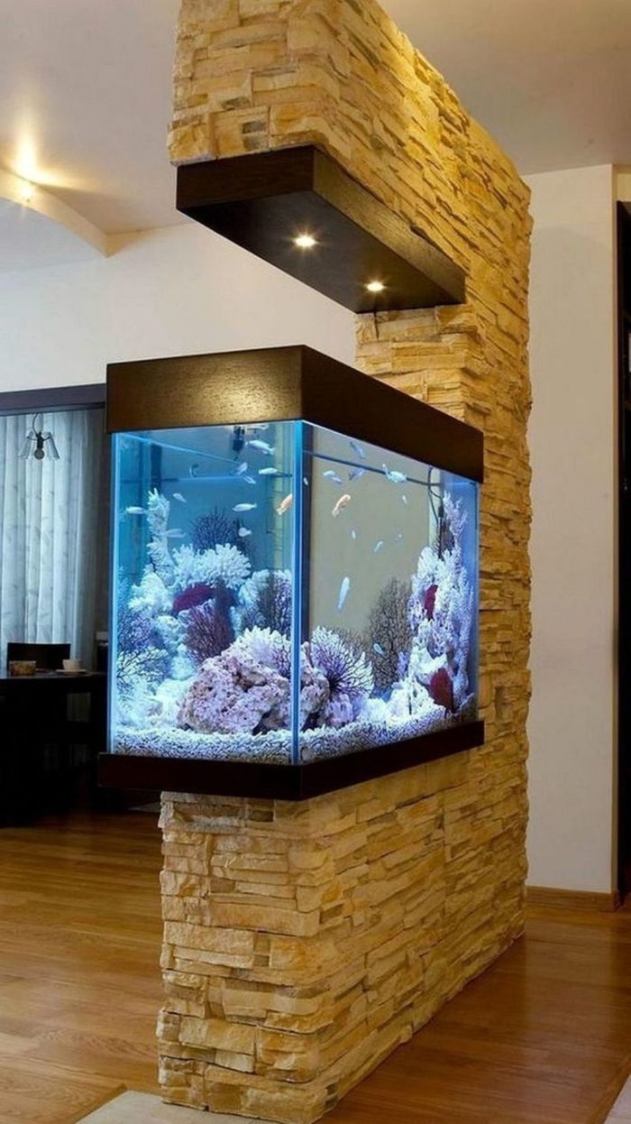 A faux stone wall with a built in aquarium and lights is a bold modern space divider to go for