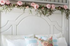 a floral pillow, a pink blanket and a garland of faux greenery and pink peonies make the bedroom feel like spring