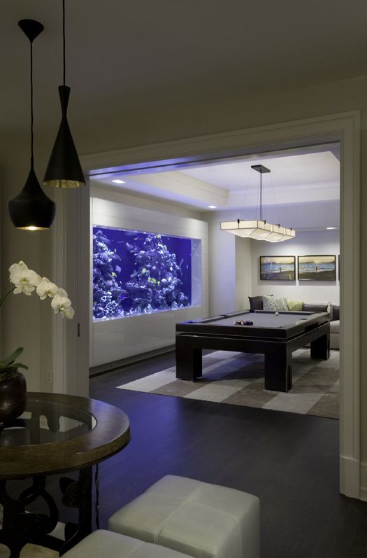a game room finished with a large aquarium that takes almost the whole wall looks very relaxing and cool