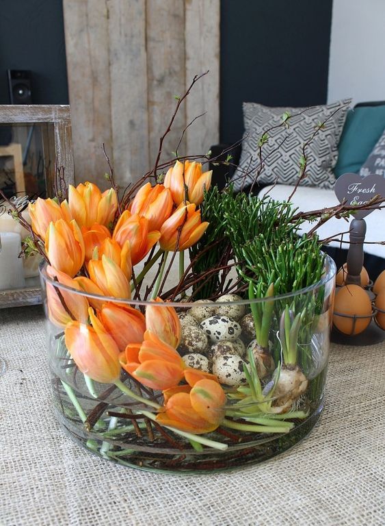 a jar with orange tulips, bulbs and speckled eggs is a bold Easter centerpiece