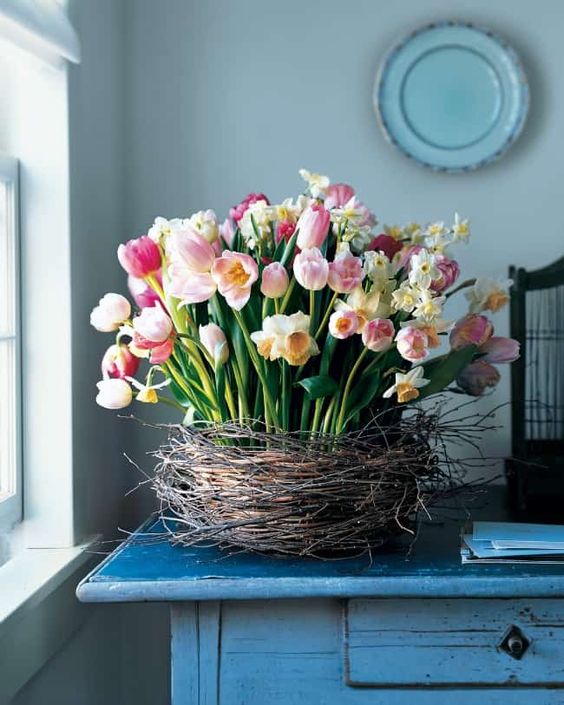 a lush flower arrangement of pink tulips and white daffodils placed in a nest screams Easter