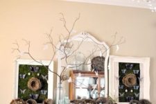 a mantel done with lots of nests with eggs, branches with paper birds and chalkboards with butterflies
