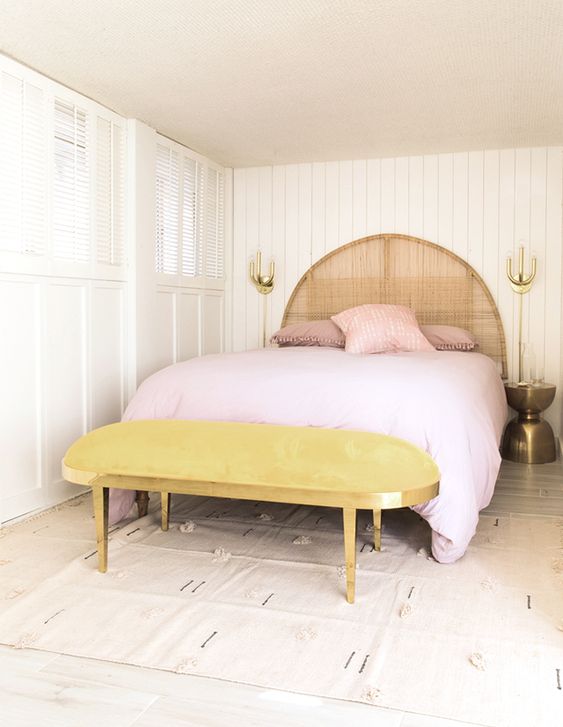 A marigold upholstered bench and pink bedding make this neutral space feel very spring like