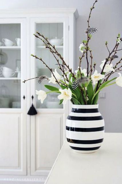 a modern Easter flower arrangement with a black and white striped vase, pussy willow, white blooms and feathers