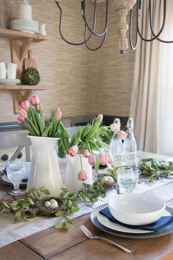a modern farmhouse spring table setting with blue and white porcelain, pink tulips and a faux nest with eggs
