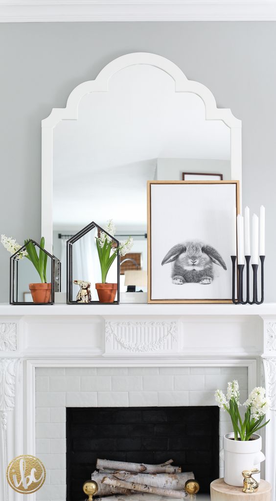 a modern spring mantel with blooming bulbs, a rabbit sign, candles in modern candle holders and a bunny figurine
