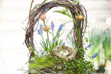 a nest Easter arrangement with a handle, grape hyacinths, other bulbs, moss and greenery and some fake eggs