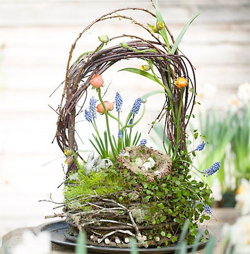 a nest Easter arrangement with a handle, grape hyacinths, other bulbs, moss and greenery and some fake eggs
